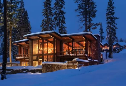 Exterior of luxury contemporary cabin in snowy forest at night