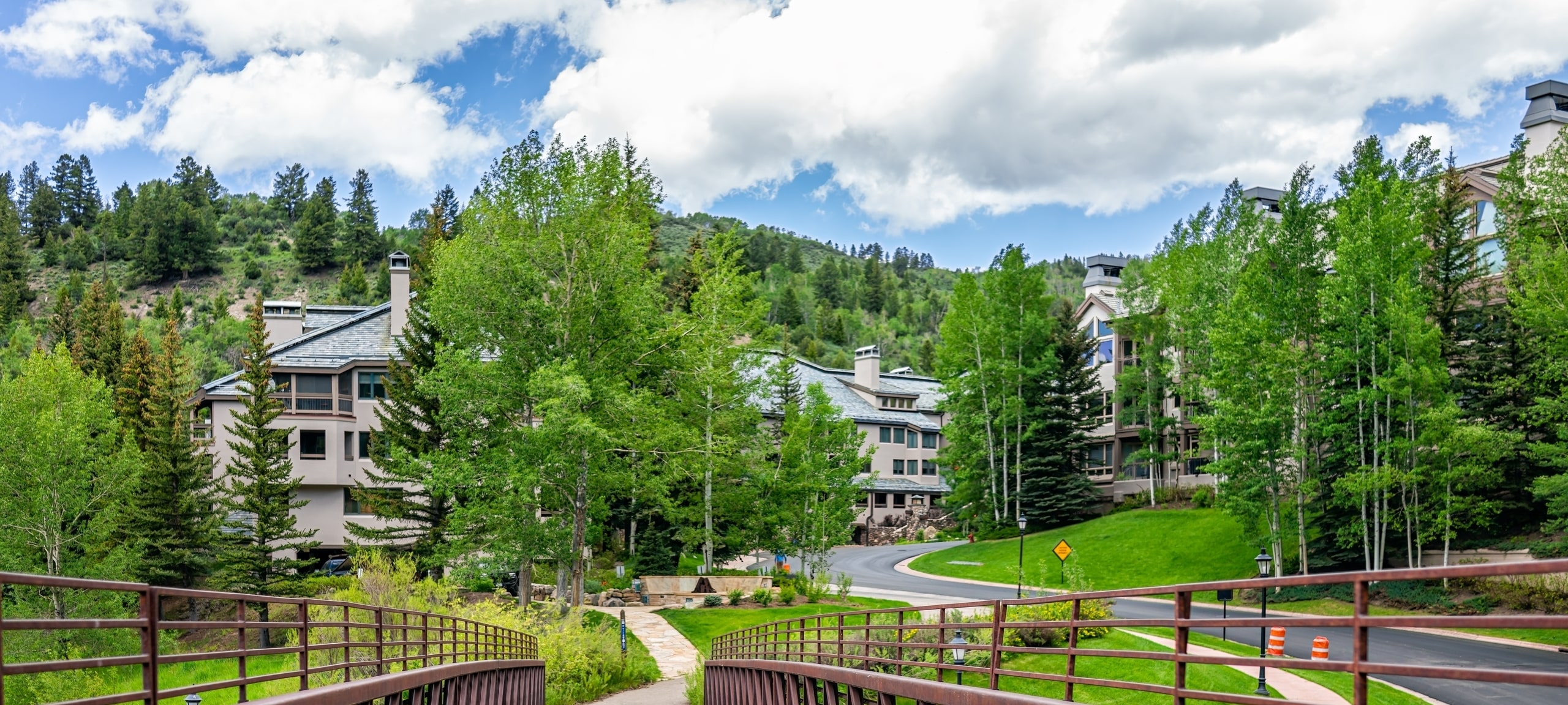 Village Loop condos in Aspen, CO with green trees and bridge